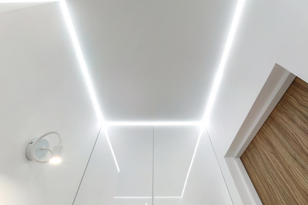 Soffitto sospeso con lampade alogene e costruzione in cartongesso in una stanza vuota in appartamento o casa Soffitto teso bianco e di forma complessa