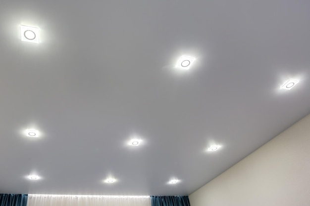 Soffitto sospeso con lampade alogene e costruzione in cartongesso in una stanza vuota in appartamento o casa Soffitto teso bianco e di forma complessa