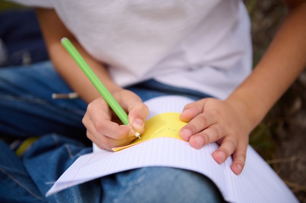 Soft focus sulle mani dello scolaro che tengono una penna e fanno i compiti, scrivendo sul quaderno, risolvendo compiti di matematica. Ritorno a scuola, conoscenza, scienza, educazione, concetti di apprendimento. Avvicinamento.