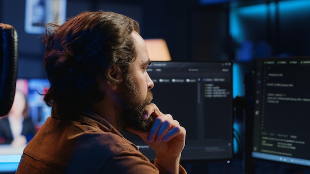 Software engineer puzzled in front of computer screen while writing complex code