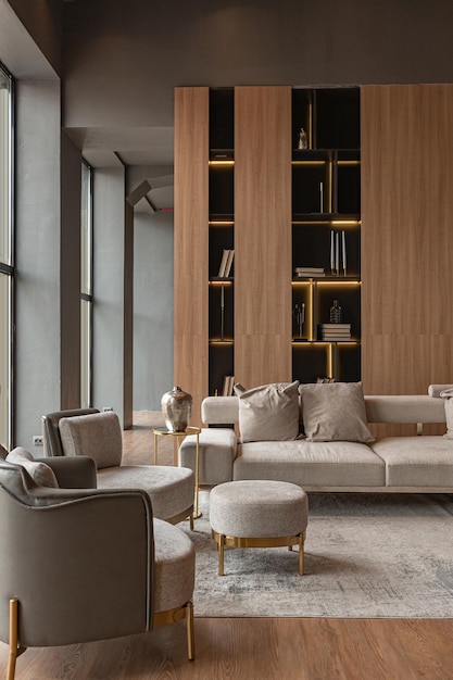 Soggiorno con camino a parete in marmo ed elegante libreria in interni eleganti e costosi di una lussuosa casa di campagna dal design moderno con mobili in legno e led grigio chiaro con elementi dorati