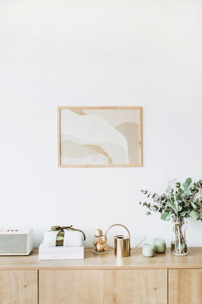 Soggiorno minimal in stile scandinavo nordico con cornice per foto sul tavolo in legno a parete bianca con confezione regalo e bouquet floreale