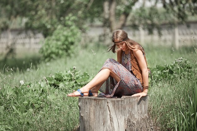 Sognando la donna hippie seduta su un grande ceppo in un parco cittadino