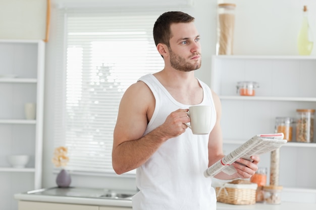 Sognando uomo che beve caffè durante la lettura delle notizie