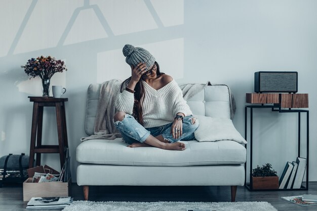 Sognare bellezza. Attraente giovane donna in abbigliamento casual e cappello lavorato a maglia che tiene la mano sulla testa