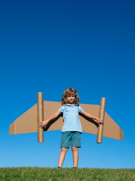Sogni di viaggio bambino che vola su jetpack con aeroplano giocattolo su sfondo cielo bambino felice che gioca dentro