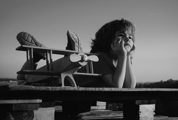 Sogni di volo bambino di un anno che gioca con l'aereo giocattolo contro il cielo sogni di viaggi little drea