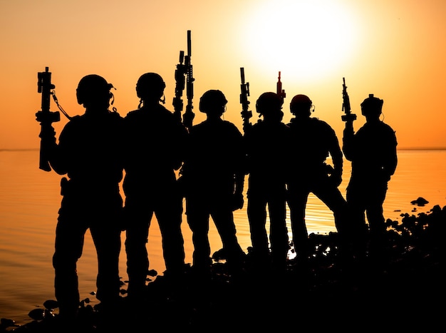 Soldati dell'esercito con fucili silhouette tramonto arancione