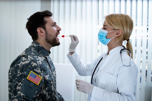 Soldato americano in uniforme che fa il test PCR presso l'ufficio dei medici durante l'epidemia di virus covid19