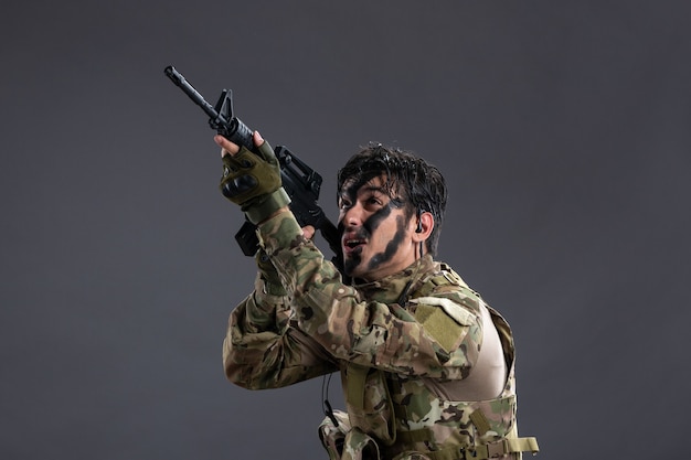 Soldato coraggioso di vista frontale che combatte in camuffamento con la parete scura della mitragliatrice