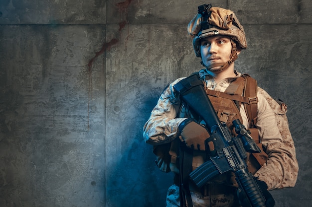 Soldato dell'esercito completamente equipaggiato in uniforme mimetica e casco, armato di pistola e fucile d'assalto