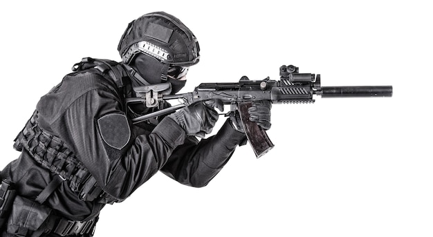 Soldato dell'esercito equipaggiato, membro d'élite delle forze speciali, combattente commando, sparatutto SWAT della polizia protetto con armatura e casco, mirando con fucile d'assalto, isolato su sfondo bianco