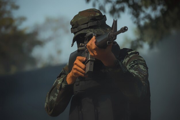 Soldato dell'esercito in uniforme protettiva tenendo il fucile. fucile d'assalto soldato delle forze speciali con silenziatore.