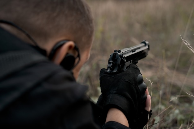 Soldato delle forze speciali in uniforme nera sdraiato e puntando una pistola