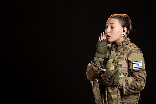 Soldato donna in mimetica con granata sul muro nero
