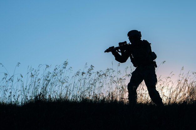 Soldato militare con armi al tramonto sparato tenendo pistola cielo colorato concetto militare