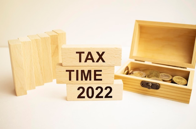 Soldi monete pila scala come passo crescita crescente e blocco cubo di legno con la parola TAX TIME 2022 Investimenti e risparmiare denaro concetto