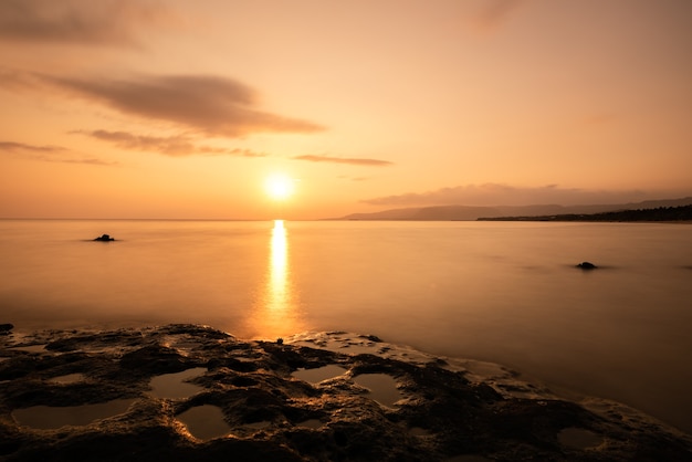 Sole che sorge all'orizzonte. Bellissimo il riflesso nell'oceano, pozzanghere formate nelle rocce illuminate dalla luce del sole.