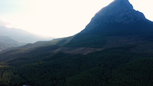 Sole che splende sopra il picco di montagna Bella scena mattutina del villaggio verde nella valle di montagna aerea dr