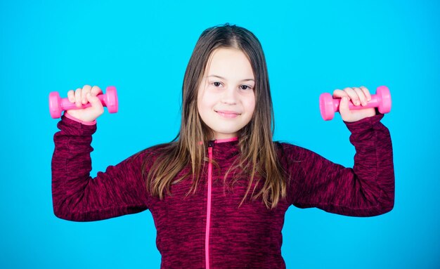 Sollevamento pesi per i muscoli Attività infantile Dieta fitness per la salute energetica Allenamento della piccola ragazza con manubri Successo sportivo Bambino sportivo felice con attività sportiva con bilanciere Attività indoor