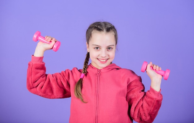 Sollevamento pesi per i muscoli Attività per l'infanzia Dieta fitness per la salute energetica Successo sportivo Bambino felice sportivo con bilanciere allenamento di piccola ragazza tenere il manubrio che lavora i suoi muscoli