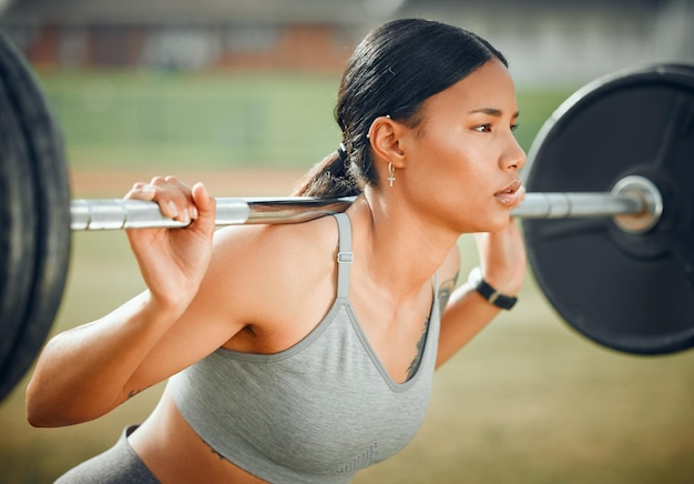 Sollevare il suo spirito Ritagliata colpo di un attraente giovane atleta femminile che si esercita con i pesi all'aperto