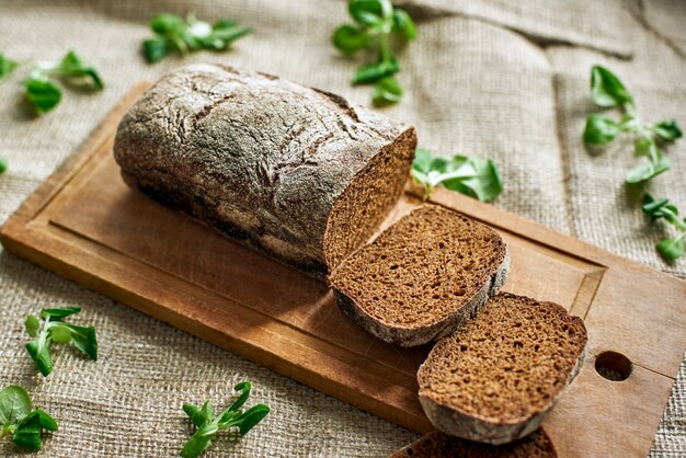 Solo cibo naturale. Vista dall'alto dell'equilibrio alimentare rustico affettato sulla scrivania di legno al tavolo, foglie di spinaci nelle vicinanze. Tovaglia di tela di juta