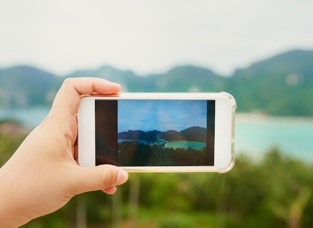 Solo un angolo di paradiso terrestre Scatto ritagliato di una persona non identificabile che utilizza uno smartphone per fotografare un paesaggio tropicale