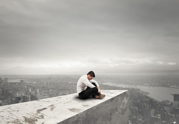 Solo un uomo d'affari disperato si siede su un tetto. solitudine e concetto di fallimento