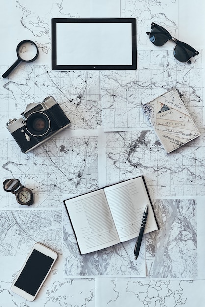 solo viaggiare. Inquadratura dall'alto di occhiali da sole, macchina fotografica, bussola, lente d'ingrandimento, diario