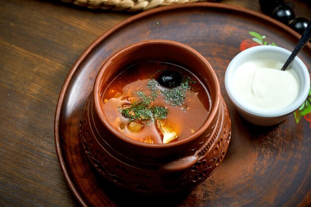 Solyanka zuppa di carne con olive salsicce affumicate al limone in una ciotola Sfondo di legno