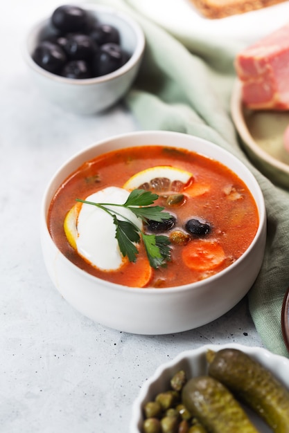 Solyanka, zuppa russa con salsiccia, olive, cetrioli sottaceto e capperi