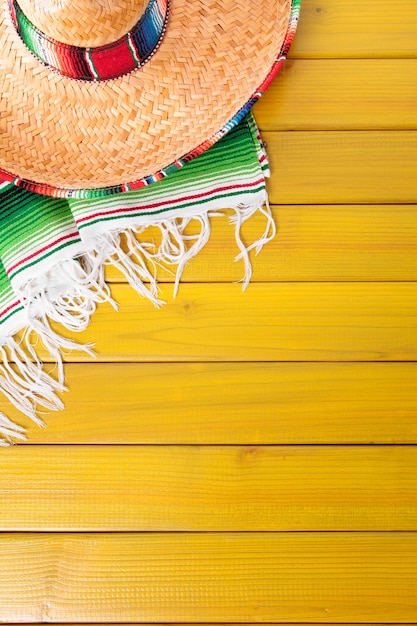 Sombrero messicano e coperta tradizionale di serape posata su un pavimento in legno di pino dipinto di giallo