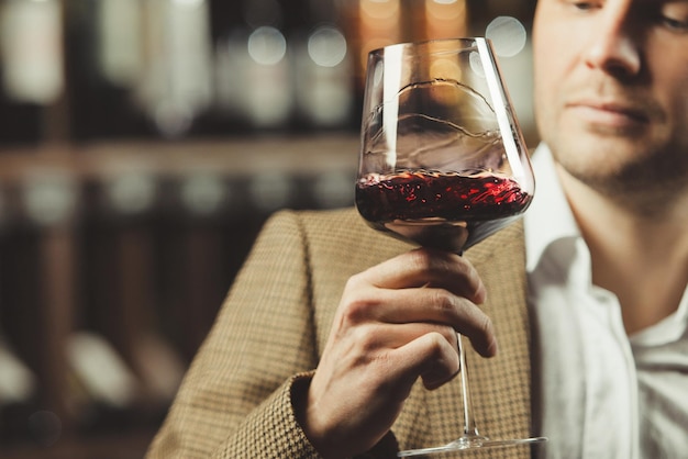 Sommelier maschio che degusta vino rosso in cantina