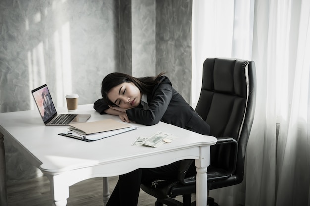 Sonno della donna di affari sul posto di lavoro dello scrittorio dopo il lavoro stanco duro.