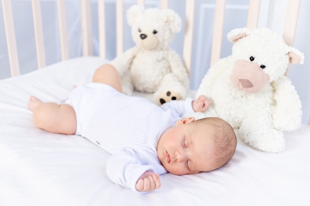 Sonno sano di un neonato in una culla in camera da letto con un orsetto di peluche su un letto di cotone