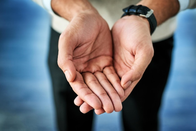 Sono davanti a te con le mani spalancate Primo piano di una persona irriconoscibile che si allunga con le mani aperte su uno sfondo blu