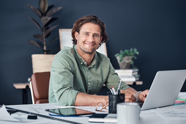 Sono in modalità di lavoro completo Ritratto di un bel giovane uomo d'affari che lavora su un laptop nel suo ufficio