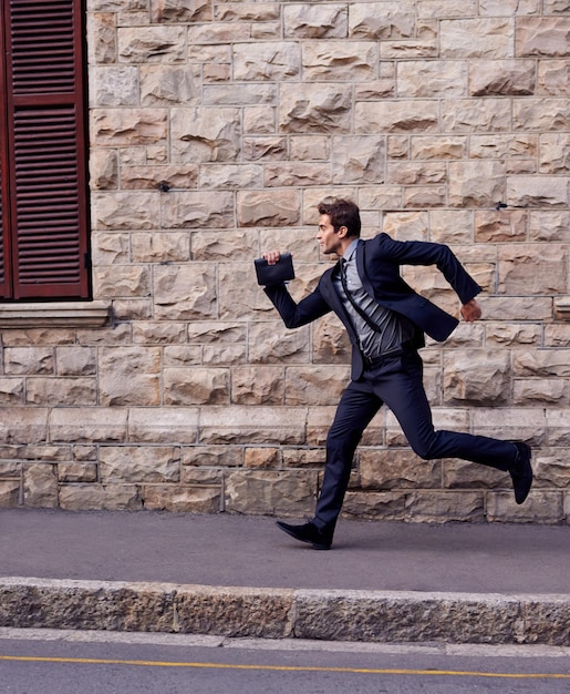 Sono in ritardo Ripresa di un giovane uomo d'affari che corre per una strada