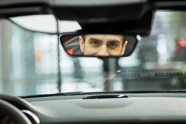 Sono sicuro della mia scelta di auto. Bei giovani seduti sul sedile anteriore dell'auto guardando lo specchietto retrovisore