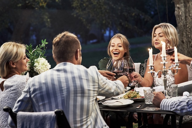 Sono tutti felici. Un gruppo di amici adulti ha una pausa e una conversazione nel cortile del ristorante la sera.