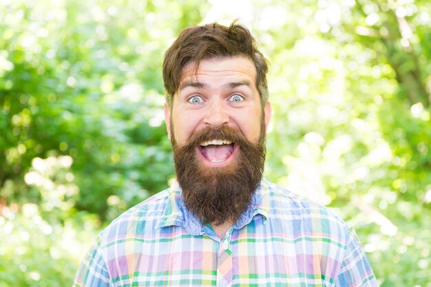 Sono un ragazzo felice. Uomo barbuto felice con un grande sorriso il giorno d'estate. Hipster caucasico con barba lunga e sorriso bianco sul viso felice. L'abitudine di essere felici.