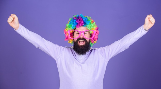 Sono un vincitore Uomo barbuto che festeggia la vittoria con una parrucca da clown Uomo in parrucca alla moda con felice gesto vincente Uomo hipster con parrucca arcobaleno Uomo felice con barba lunga e parrucca arricciata