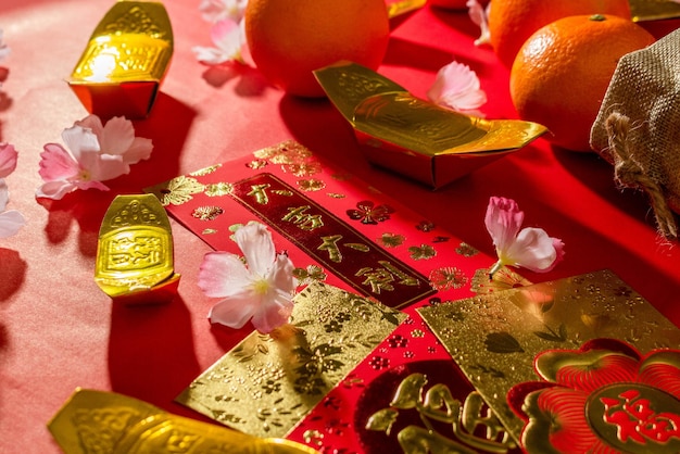 Sopra gli accessori della vista del capodanno cinese o del festival del giorno dell'umore arance oro e tasche Angpao con decorazioni di rami di fiori di ciliegio.