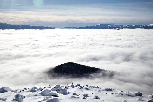 Sopra il mare di nebbia nelle montagne invernali. Giornata di sole nelle montagne dei Carpazi innevate. Nubi sopra il cielo sereno