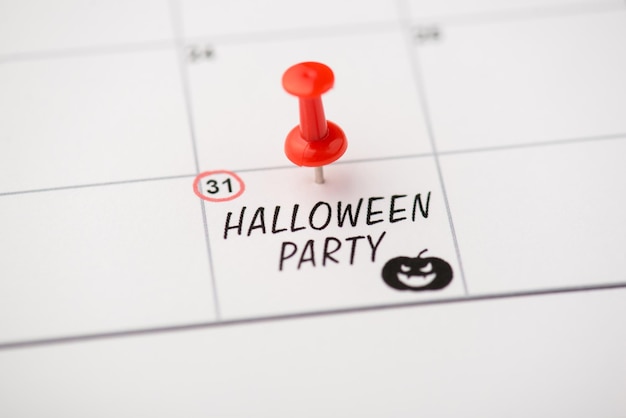 Sopra la foto dell'etichetta data 31 ottobre con scritta halloween party pin rosso e zucca isolati sullo sfondo del calendario