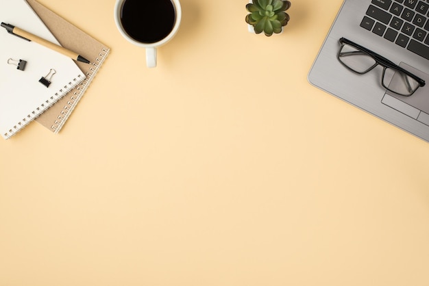 Sopra la foto della pianta e della tazza di caffè degli occhiali delle graffette della penna del taccuino del computer portatile isolata sullo sfondo beige con uno spazio vuoto