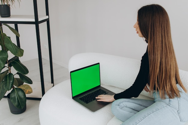 Sopra la spalla di una donna che scrive su un computer portatile con uno schermo keygreen