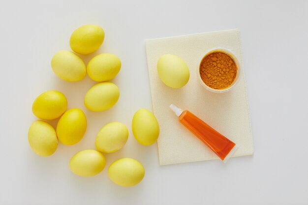 Sopra la vista del giallo pastello delle uova di Pasqua con colorante di colore naturale disposto in una composizione minima su sfondo bianco, copia dello spazio