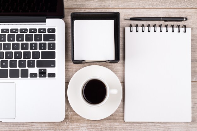 Sopra la vista del posto di lavoro dell'uomo d'affari. Tazza di caffè, laptop, taccuino e penna. Concetto di affari, istruzione o blog.